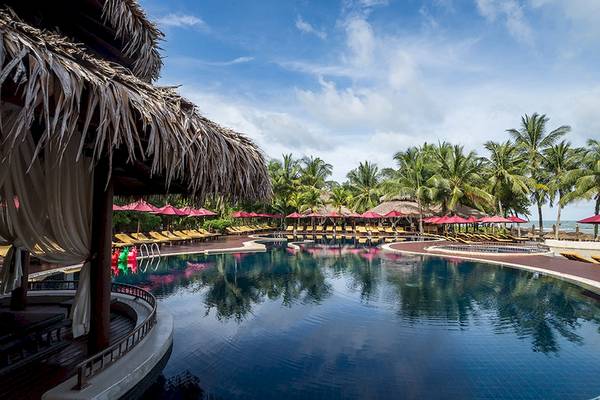 Außenpoolbereich des Khao Lak Laguna Resorts mit gelben Sonnenliegen und roten Sonnenschirmen.