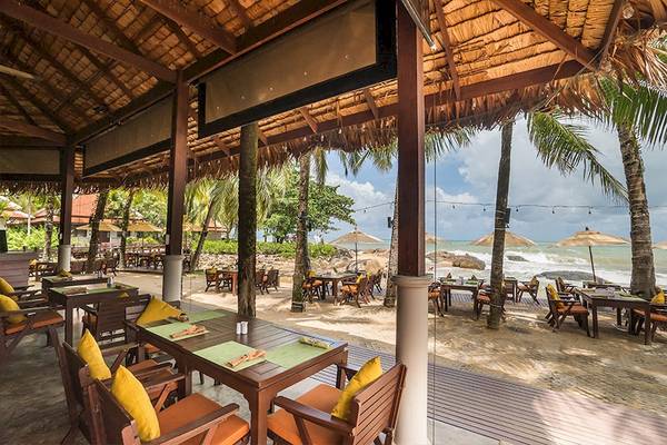 Außenbereich des Khao Lak Laguna Resorts mit Tischen und Stühlen, die einen Blick auf den Strand bieten.