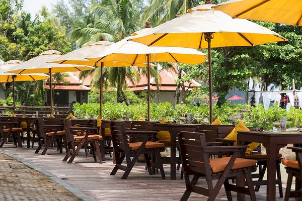 Außenterrasse mit Tischen und Stühlen unter gelben Sonnenschirmen im Khao Lak Laguna Resort