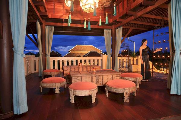 Terrasse im Khao Lak Laguna Resort mit Nachtbeleuchtung und einer Frau, die Kerzen hält
