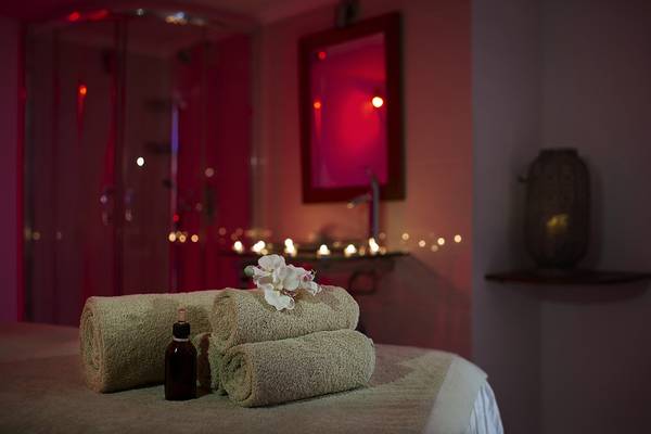 Relaxationsraum im Grecian Sands Hotel mit beleuchteten Kerzen und Blumen auf einem Bett.