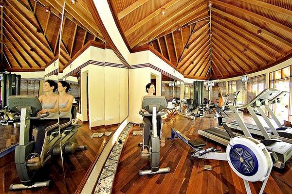 Fitnessstudio im Anantara Dhigu Maldives Resort mit Frauen auf Laufbändern und Rudergeräten.