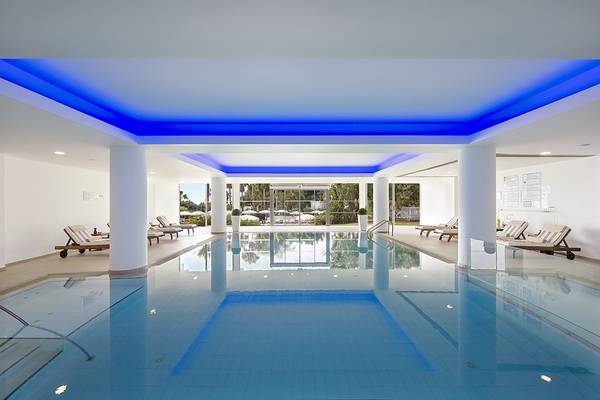 Innenpool des Grecian Sands Hotels mit blauen Lichtern und weißen Säulen.