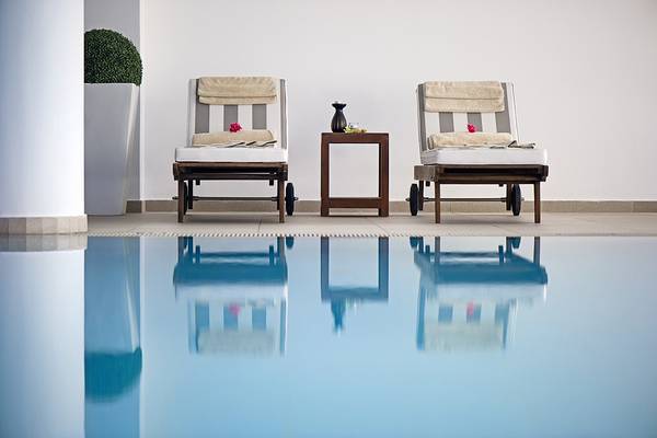 Ein Pool mit zwei Liegen und einem Tisch neben dem Grecian Sands Hotel