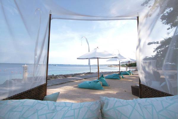 Strandlounge im Novotel Bali Benoa mit blauen Kissen und weißen Sonnenschirmen