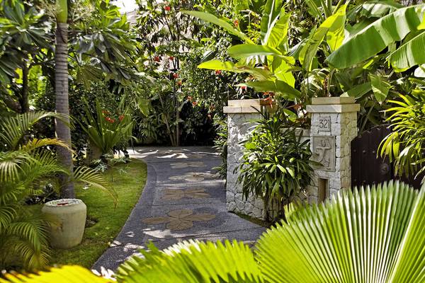 Gartenweg zum Novotel Bali Benoa Hotel mit Steinsäulen und Palmblättern.