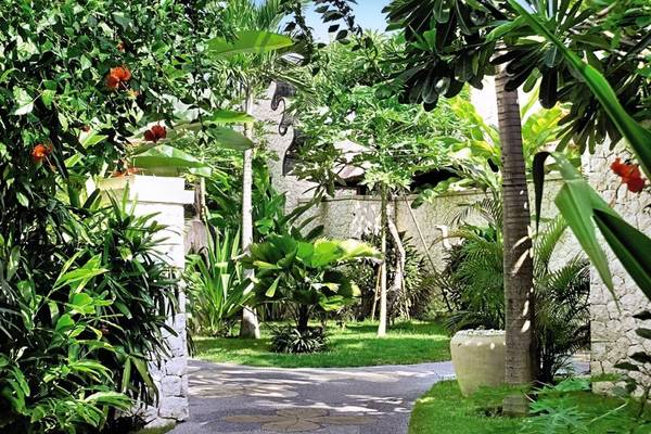 Garteneingang zum Novotel Bali Benoa mit Palmen, Pflanzen und Gehweg
