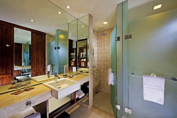 Novotel Bali Benoa Badezimmer mit Spiegeln, Waschbecken und Dusche.