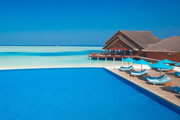 Außenpool und Loungebereich des Anantara Dhigu Maldives Resorts mit Blick auf das Meer.