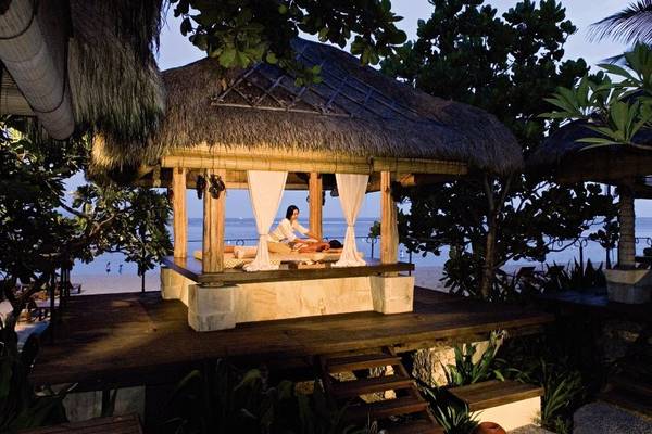 Massagehütte unter dem Himmel im Novotel Bali Benoa mit einer Frau, die sich entspannt.