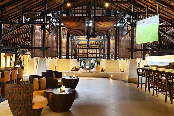 Innenansicht des Novotel Bali Benoa Hotels mit Loungebereich, Tischen und Fernseher.