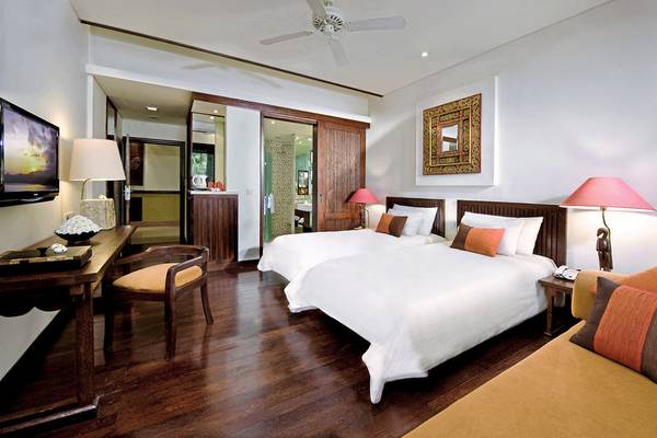 Innenansicht eines Zimmers im Novotel Bali Benoa mit zwei Betten, Holzmöbeln und einer Fernseher.