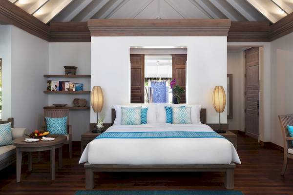 Schlafzimmer im Anantara Dhigu Maldives Resort mit einem Bett, Nachttischen, Lampen und Möbeln.