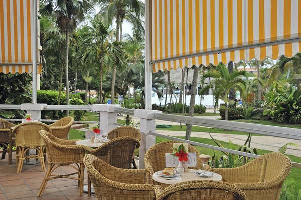 Außenterrasse des Melia Varadero Hotels mit Rattanmöbeln und gelben Sonnenschirmen.