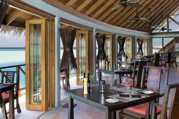 Innenansicht des Restaurants im Anantara Dhigu Maldives Resort mit Blick auf das Meer.