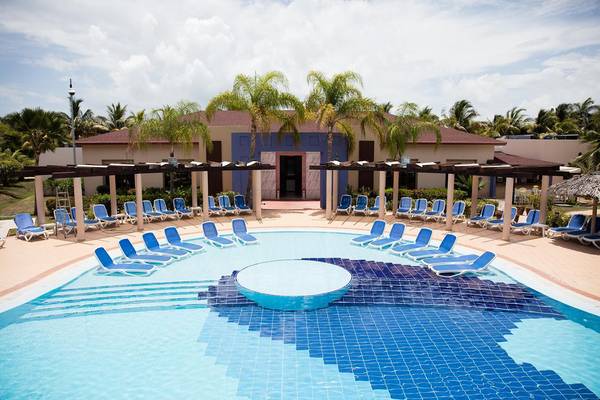Poolbereich des Melia Varadero Hotels mit vielen Liegestühlen und Palmen.