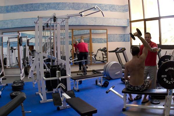 Fitnessraum im Melia Varadero Hotel mit Geräten und einem Mann, der Gewichte hebt.