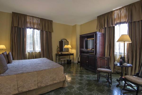 Schlafzimmer im Melia Varadero Hotel mit Bett, Nachttischen und Fernseher.