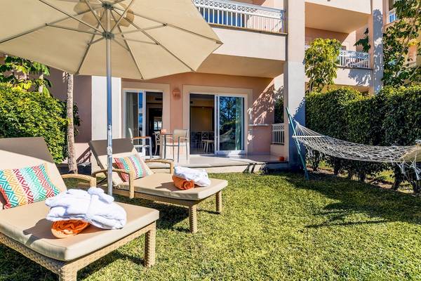 Außenbereich des Viva Blue & Spa Hotels mit Liegestühlen, Sonnenschirm und Hängematte.