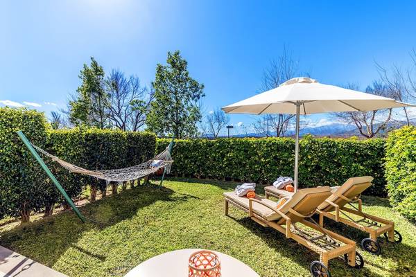 Gartenbereich des VIVA Blue & Spa Hotels mit Liegen, Sonnenschirm und Hängematte.