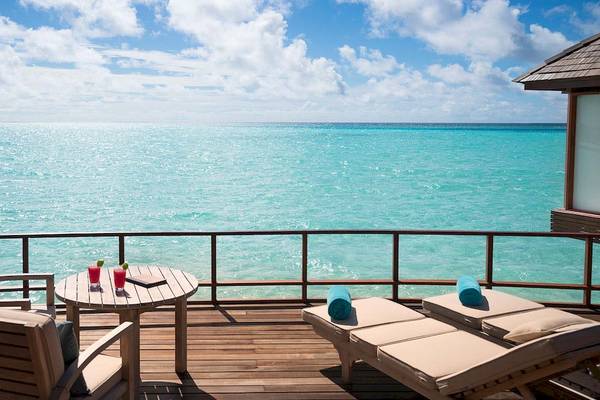 Aussicht auf das Meer von der Terrasse des Anantara Dhigu Maldives Resorts mit Tischen, Stühlen und Handtüchern.