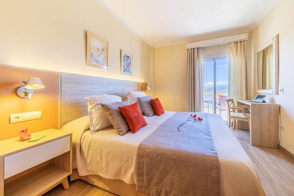 Innenansicht eines Hotelzimmers im VIVA Blue & Spa, mit Bett, Schreibtisch und Balkon.