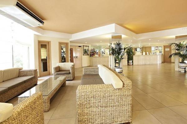 Lobby des Sandos El Greco Beach Hotels mit Möbeln, Pflanzen und Klimaanlage.