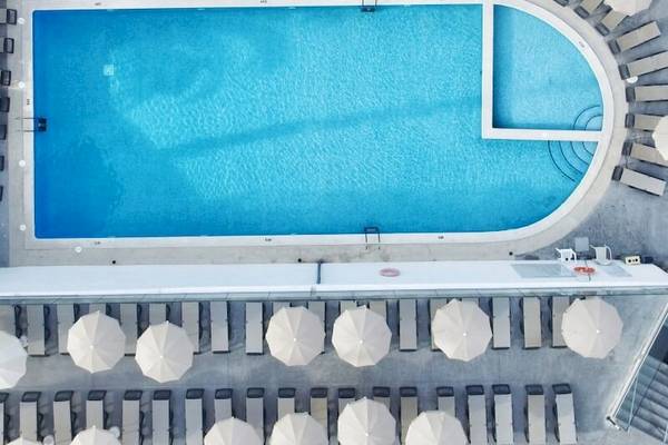 Luftaufnahme des Sandos El Greco Beach Pools mit Sonnenliegen und Sonnenschirmen