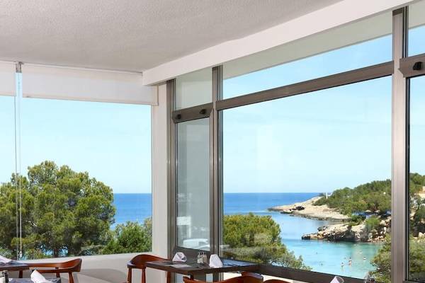 Sandos El Greco Beach Hotel Innenrestaurant mit Meerblick, gedeckte Tische und Stühle, große Fenster mit Blick auf das Meer.