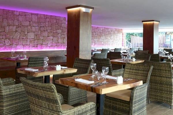 Innenansicht des Restaurants im Sandos El Greco Beach Hotel mit steinerner Wand und lila Beleuchtung.