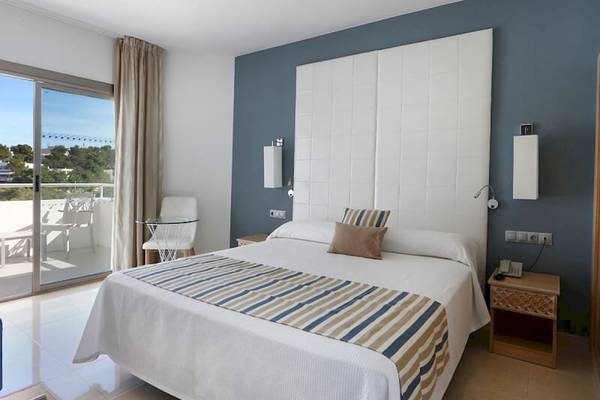 Schlafzimmer im Sandos El Greco Beach Hotel mit Bett, Balkon und modernen Möbeln.