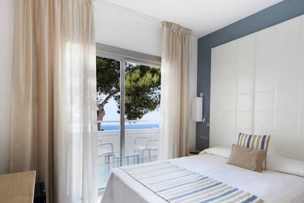 Schlafzimmer im Sandos El Greco Beach Hotel mit Blick auf das Meer und einen Balkon.