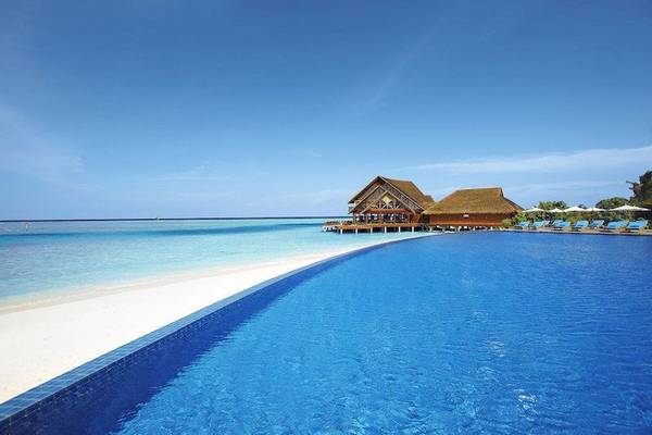 Der Anantara Dhigu Maldives Resort mit einem großen Infinity-Pool und einer Strandbar.