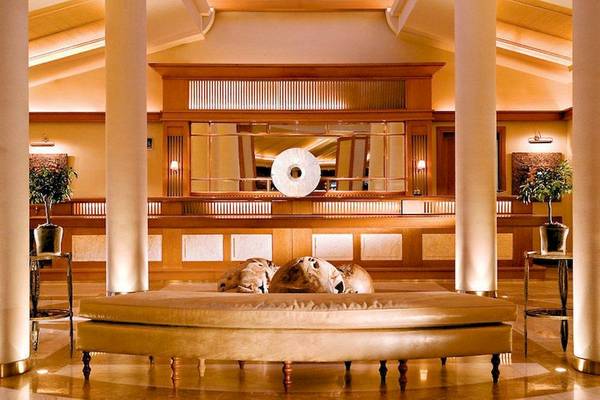 Lobby des Porto Sani Hotels mit Ledersofa, Säulen und Pflanzen.