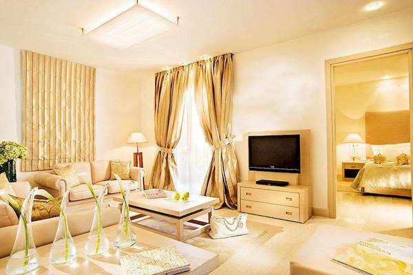 Wohnzimmer des Porto Sani Hotels mit Sofa, Tisch, Fernseher und Fenstern mit goldenen Vorhängen