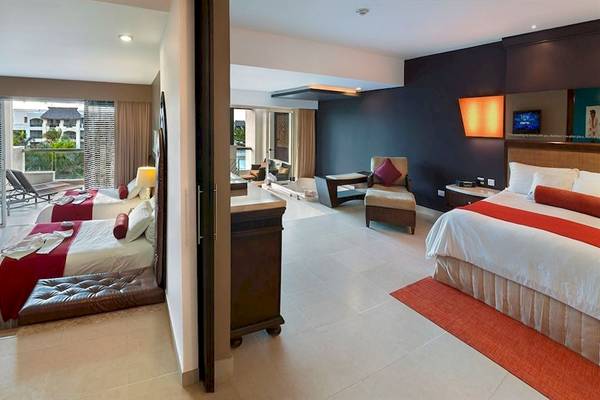 Suite-Innenansicht im Hard Rock Hotel & Casino Punta Cana mit zwei Betten, Fernseher, Möbeln und Aussicht.