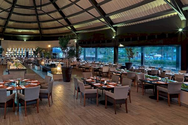 Innenansicht des Restaurants im Hard Rock Hotel & Casino Punta Cana mit Holzböden und großen Fenstern.