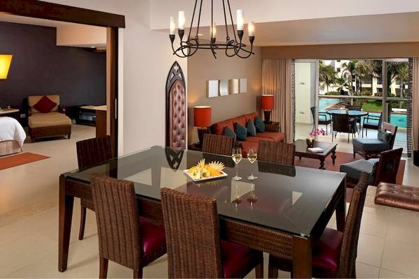 Innenansicht der Suite im Hard Rock Hotel & Casino Punta Cana mit Esstisch, Couch und Poolblick.