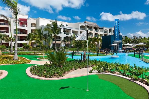 Minigolfplatz vor dem Hard Rock Hotel & Casino Punta Cana mit Gebäuden und Palmen im Hintergrund.