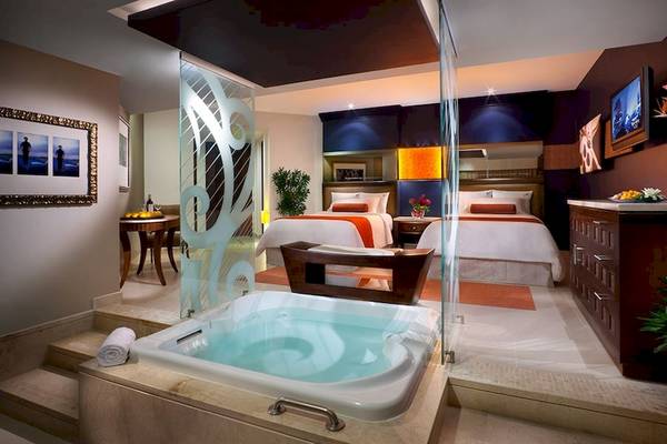 Suite Zimmer im Hard Rock Hotel & Casino Punta Cana mit Jacuzzi, Betten, Fernseher und Pflanzen.