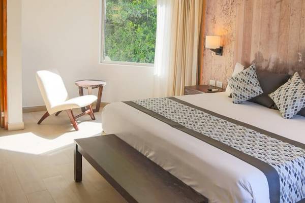Schlafzimmer im Sandos Caracol Eco Resort mit Bett, Stuhl und Fenster