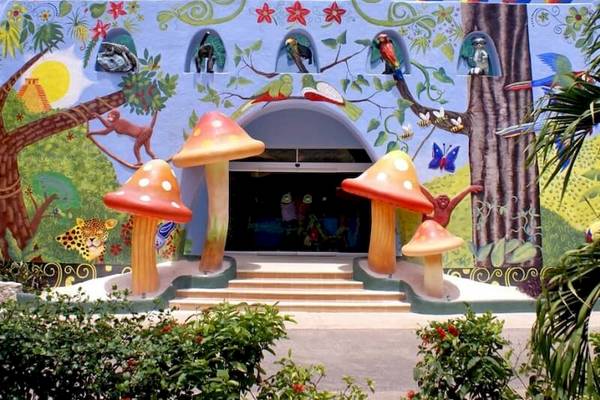 Eingang zum Kinderclub im Sandos Caracol Eco Resort mit bunten Wandmalereien und Pilzskulpturen.