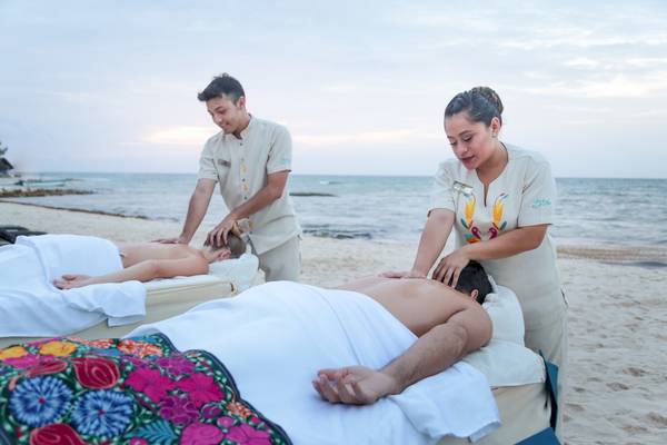 Massage am Strand im Sandos Caracol Eco Resort mit zwei Therapeuten und Klienten