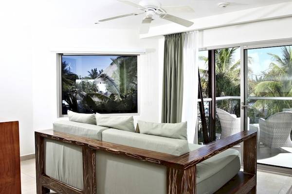 Wohnzimmer im Sandos Caracol Eco Resort mit Sofa, Tisch und Terrassentür zu einem Balkon