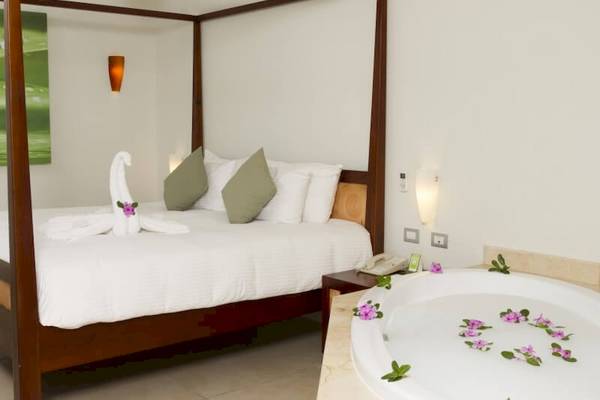 Suite im Sandos Caracol Eco Resort mit Bett und Badewanne im Zimmer.