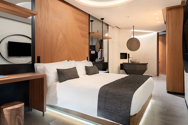 Hotelzimmer im Faro, Lopesan Collection Hotel mit weißem Bett, Holzwänden und modernem Design.