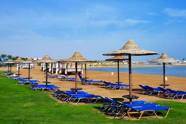 Strand des Jaz Aquamarine Resorts mit blauen Sonnenliegen und Strohschirmen