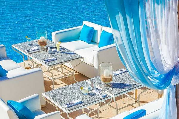 Loungebereich mit weißen Möbeln und blauen Kissen am Pool des Jaz Aquamarine Resorts.