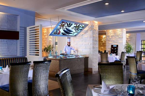 Innenansicht des Restaurants im Jaz Aquamarine Resort mit einem Koch, der Fisch präsentiert.