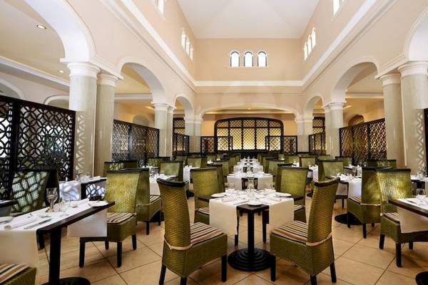 Innenansicht des Restaurants im Jaz Aquamarine Resort mit runden Tischen und Stühlen.
